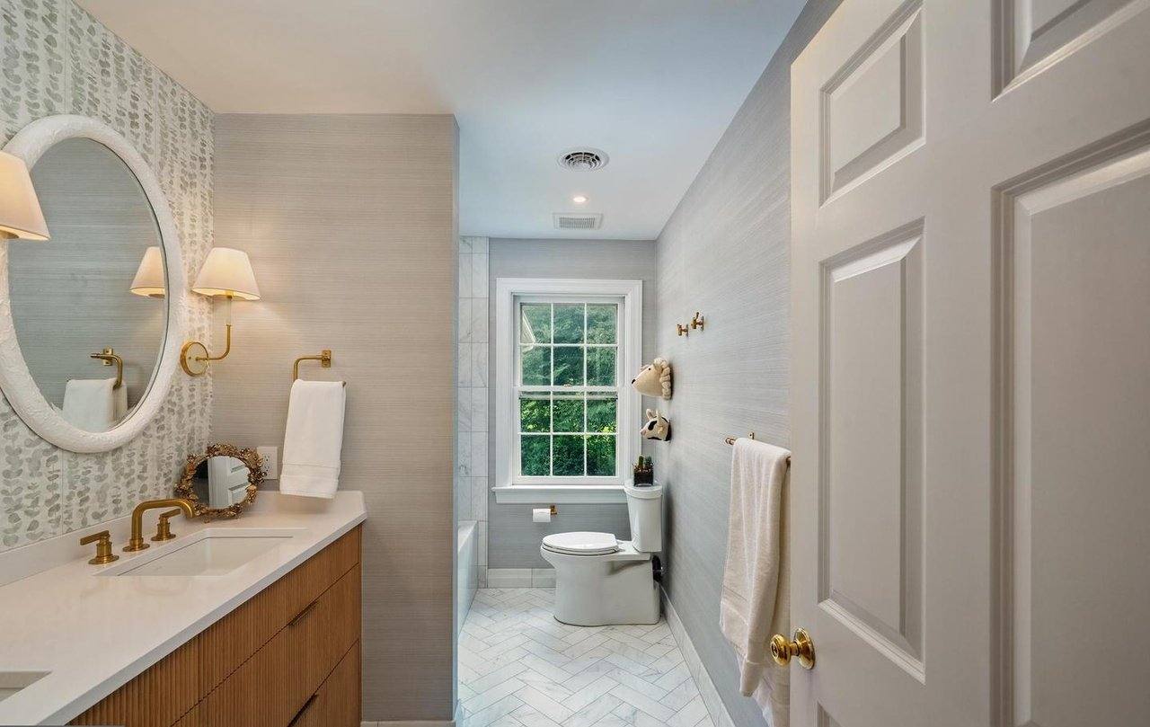 Bathroom with a white oak vanity, brass fixtures and grasscloth walls