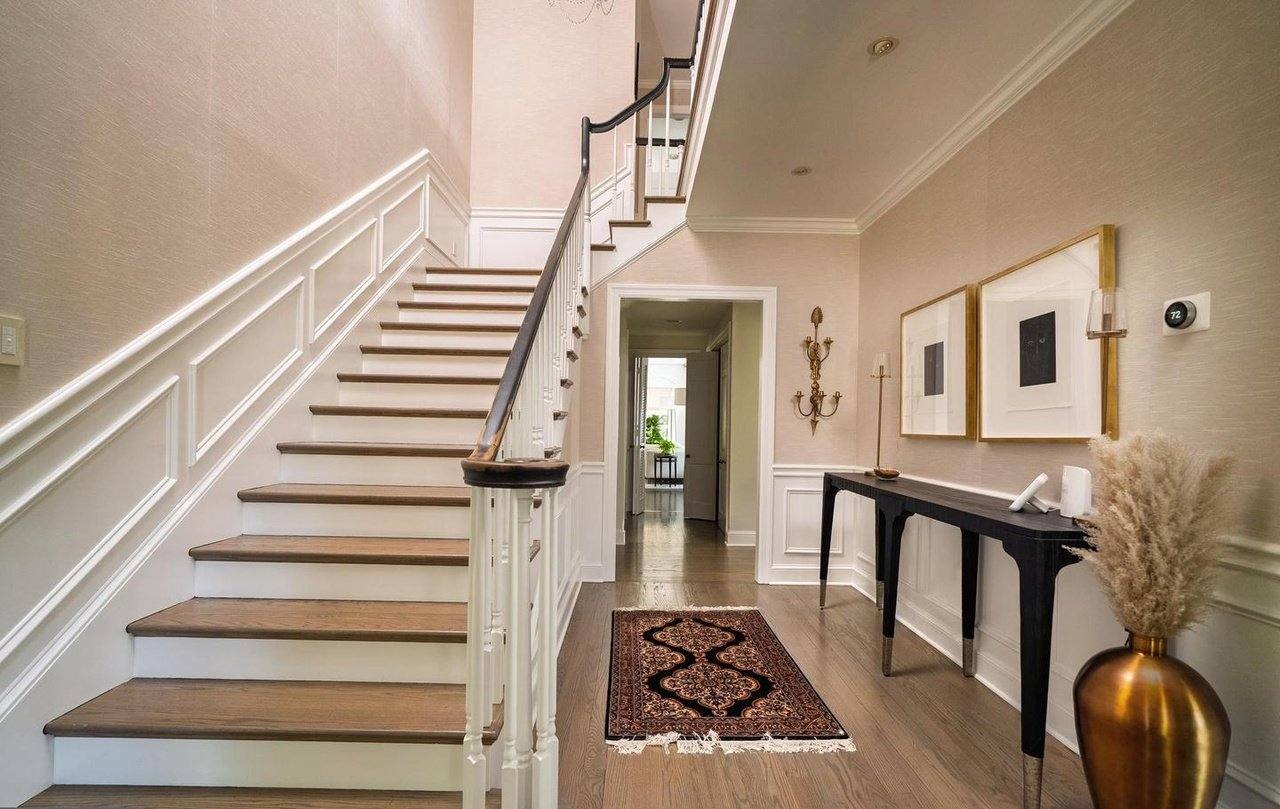 Entry foyer with paneled walls and a refinished staircase
