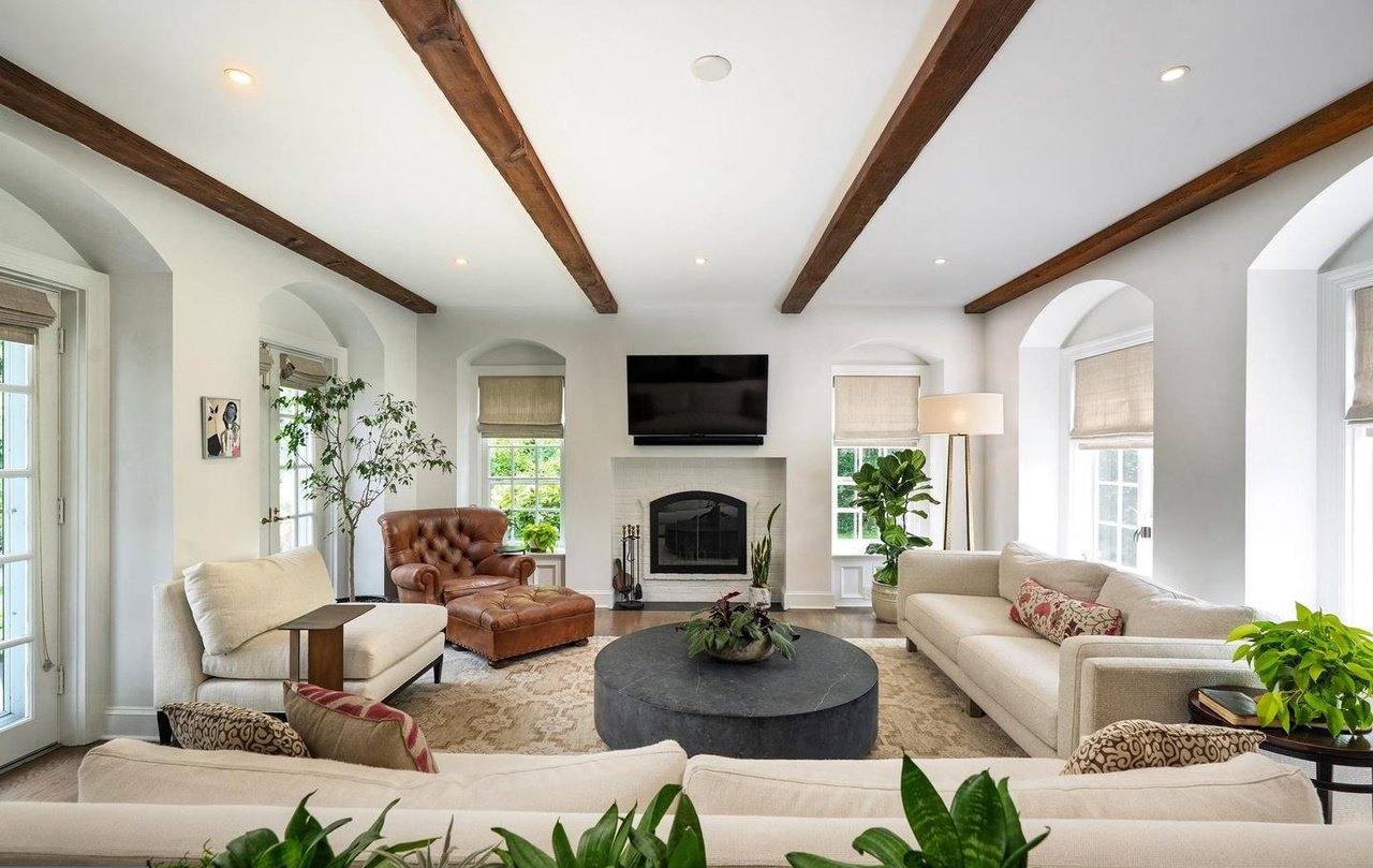 Family room with exposed wood beams, arched doorways and a fireplace