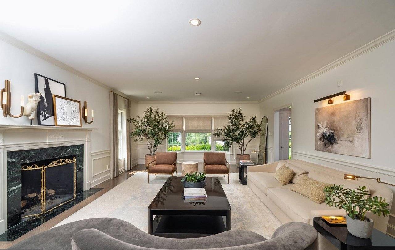 Living room with a marble fireplace, built-in millwork and hardwood floors