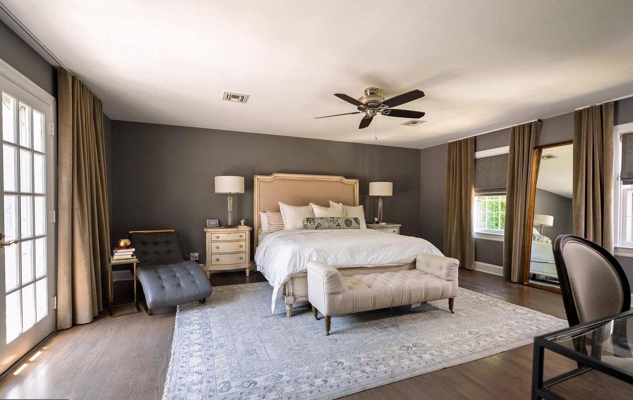 Primary bedroom with hardwood floors and tall windows