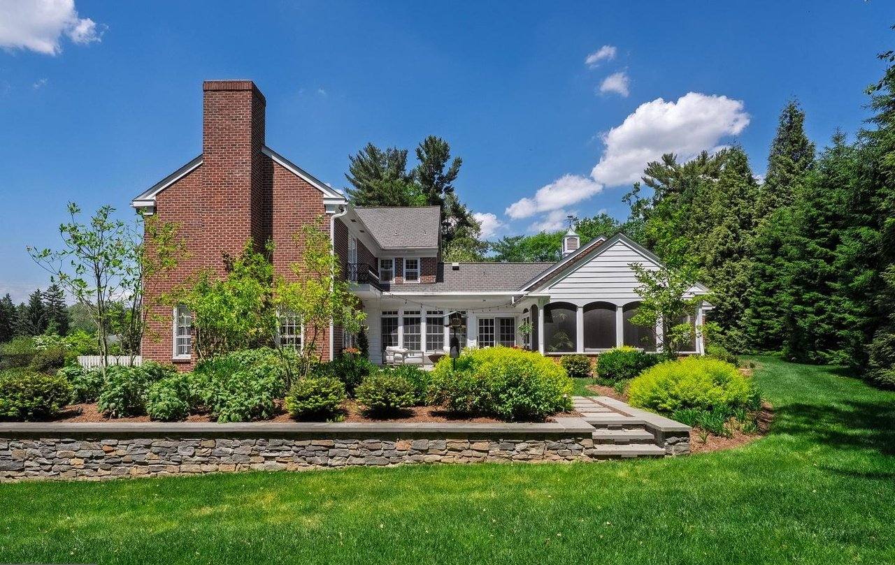 Rear of the house with lawn, layered plantings and a stone retaining wall